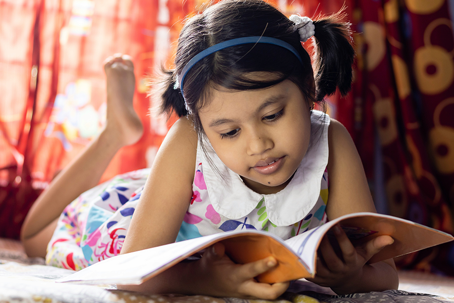Young girl sitting on the floor with an open book