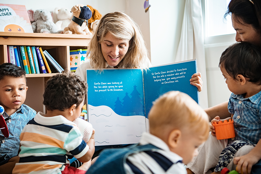Librarian holding up a picture book to show a group of young children