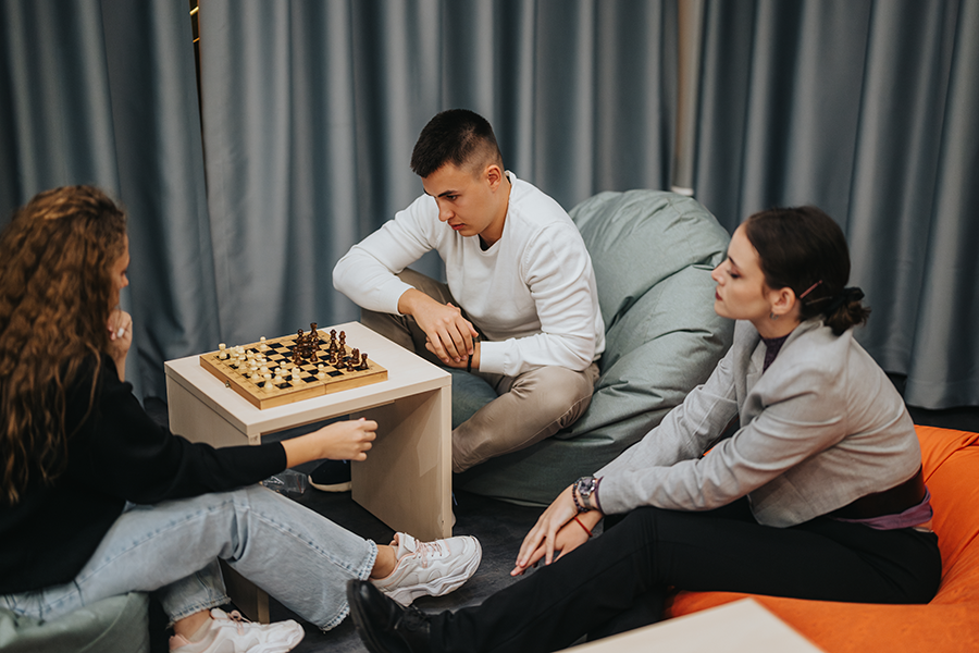 Group of three teens, two girls and one boy, playing chess
