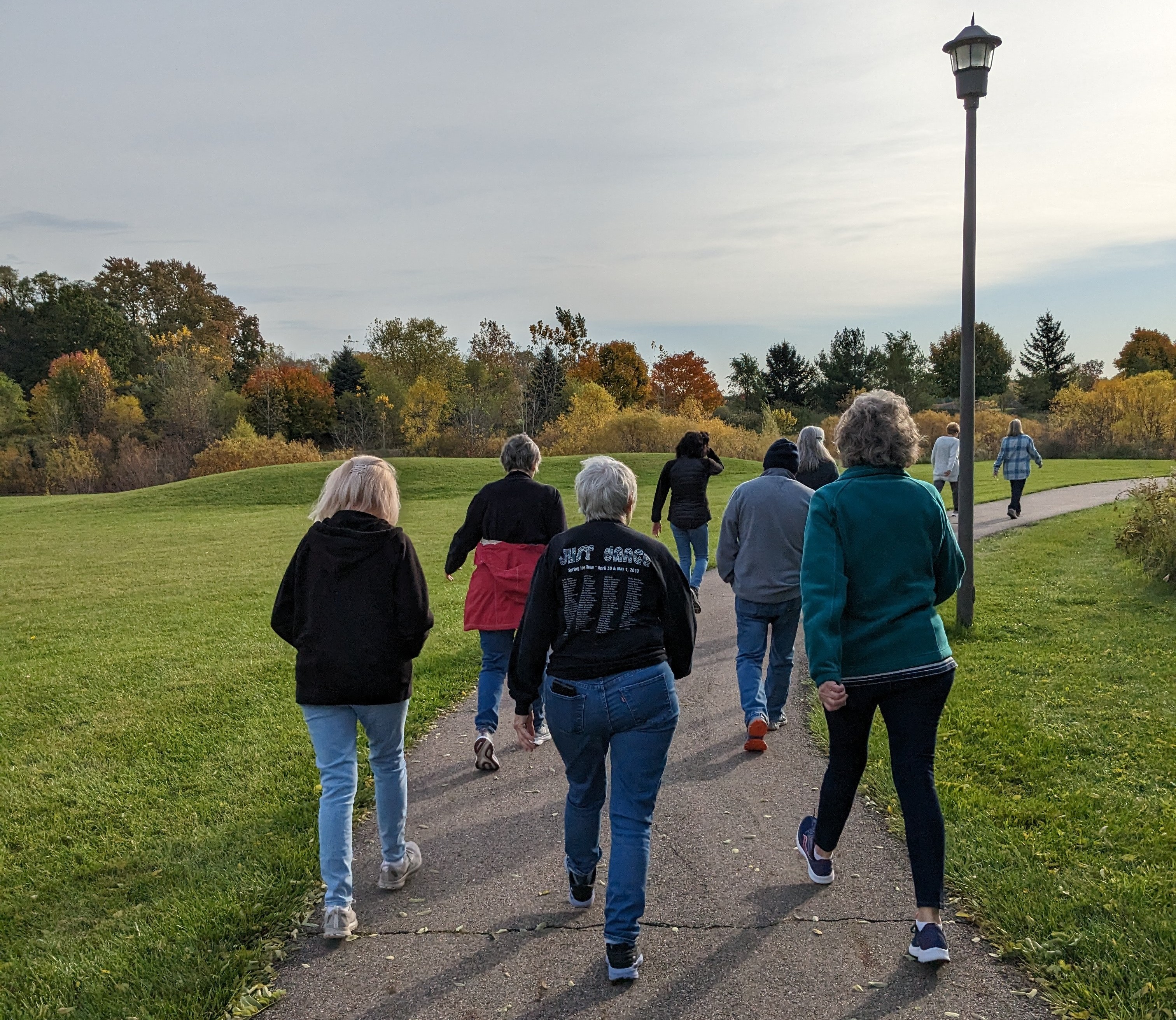 a group of people walk away from the camera on a paved walking path