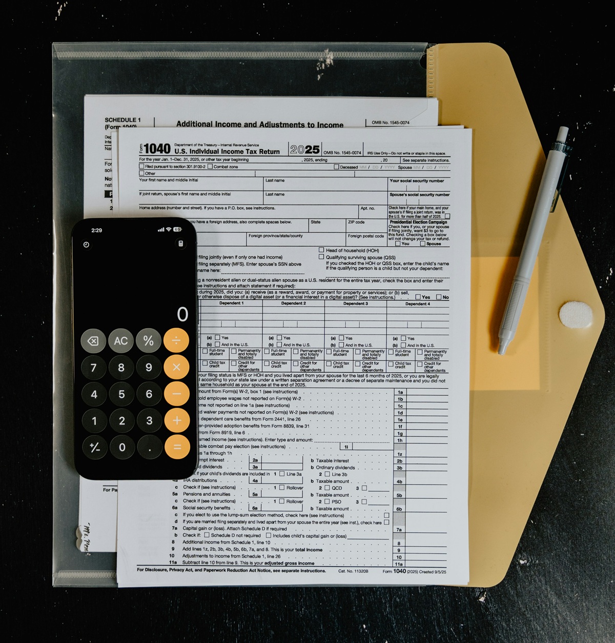 Federal 1040 tax form sits on a table with a calculator and a pen