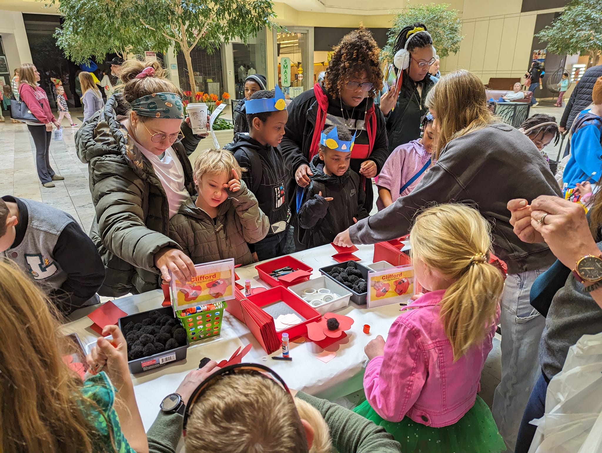 a group of people standing around a table working on a craft project