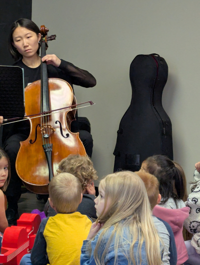 woman playing the cello for a group of children