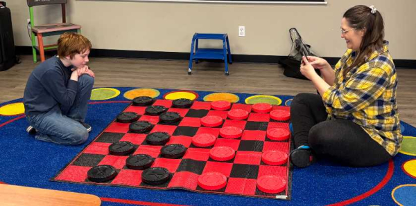 Adult and Child sitting on the floor with a Giant Checkers game