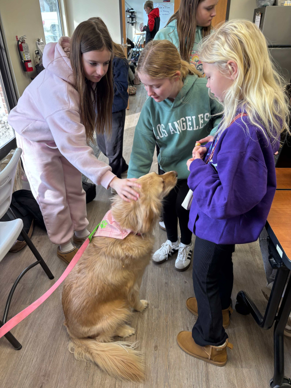 three girls pet a yellow lab