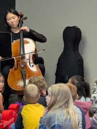 woman playing the cello for a group of children