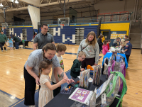 Parents and kids looking at material at a STEAM event table