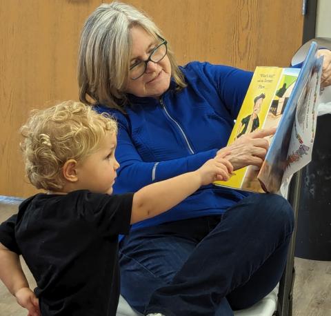 child and elderly adult reading a book together