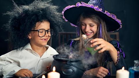boy and girl pouring liquid into a caldron 