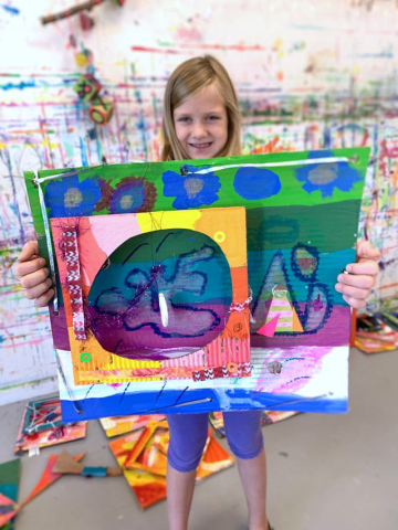 girl holding a piece of art made from upcycled materials