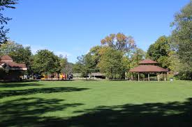 large area of green grass with park structures in the background